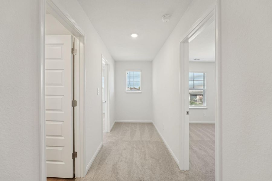 Corridor with light carpet and baseboards
