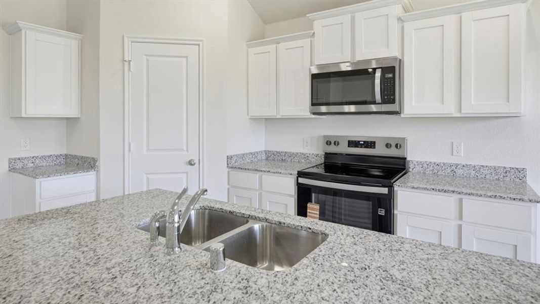 Kitchen with appliances with stainless steel finishes, white cabinets, and light stone counters Kitchen with appliances with stainless steel finishes, white cabinets, and light stone counters