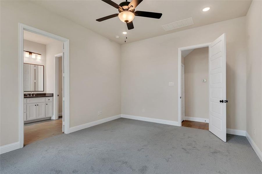 Unfurnished bedroom featuring ensuite bath, sink, ceiling fan, and light colored carpet