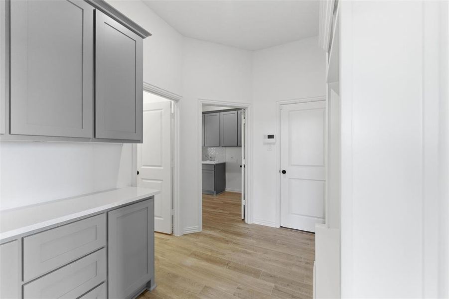 Hallway featuring light wood-style flooring, white walls, and white doors with black hardware