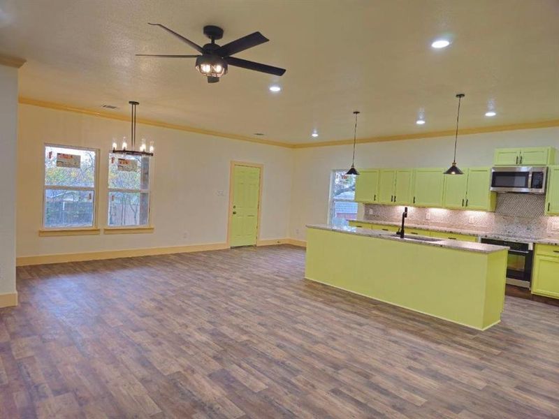 Kitchen with a wealth of natural light, pendant lighting, stainless steel appliances, and a center island with sink