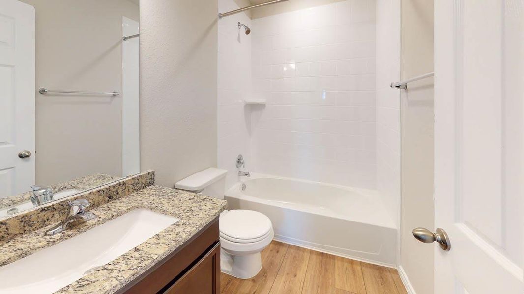 Bathroom featuring vanity, tub / shower combination, light wood-type flooring, and a textured wall