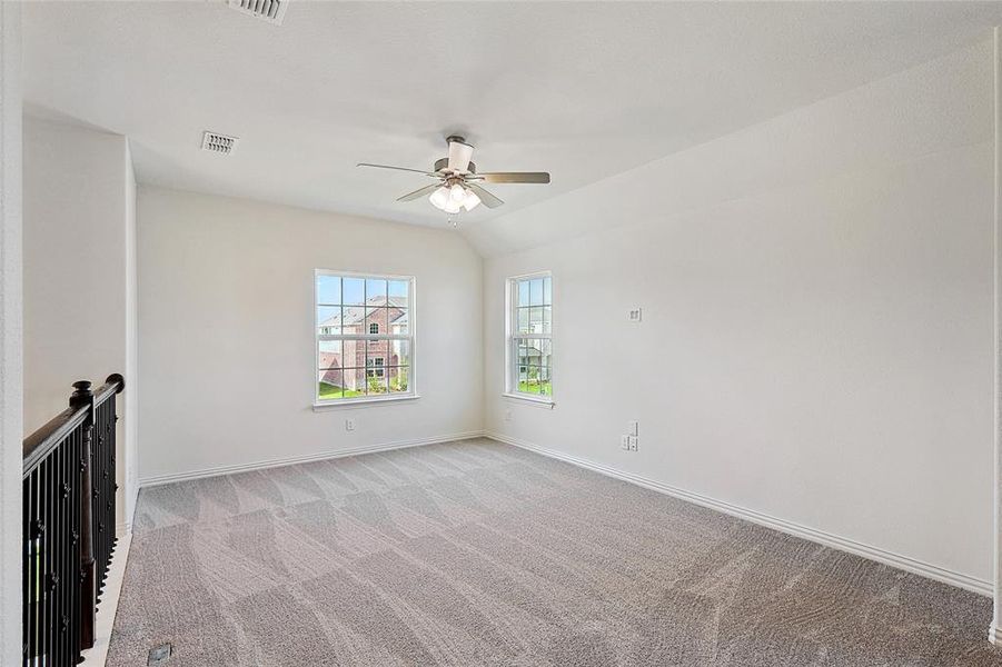 Carpeted empty room with ceiling fan and vaulted ceiling