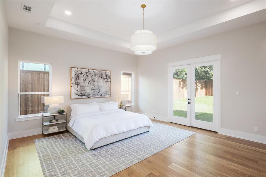 Bedroom featuring access to outside, hardwood / wood-style flooring, french doors, and a tray ceiling