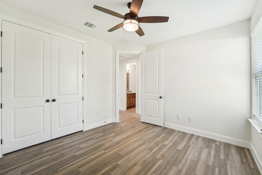 Bedroom 3 featuring baseboards, wood-style vinyl flooring, visible vents, and a closet Bedroom 3 featuring baseboards, wood-style vinyl flooring, visible vents, and a closet