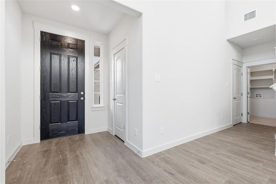 Entryway featuring a dark wood door with panel detailing, a vertical sidelight, and wood-finish flooring Entryway featuring a dark wood door with panel detailing, a vertical sidelight, and wood-finish flooring