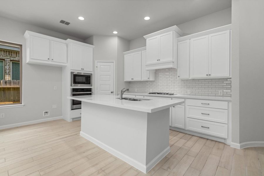 Modern kitchen featuring a large center island, white cabinetry, recessed lighting and generous workspace.