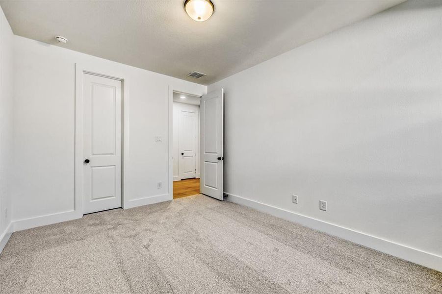 Unfurnished bedroom featuring light carpet and baseboards