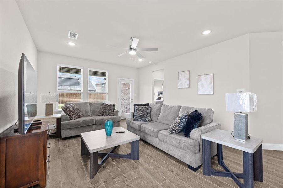 The expansive layout easily accommodates larger sofas with room for accent tables and consoles with room to spare, while recessed lighting and a sleek ceiling fan keep the space feeling open, modern, and inviting.