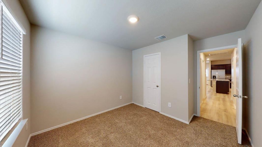 A well-lit room offering plush carpeting and a clear view into the adjacent kitchen. A well-lit room offering plush carpeting and a clear view into the adjacent kitchen.