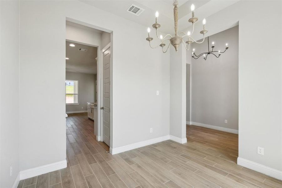 Unfurnished room with a chandelier and light hardwood / wood-style floors