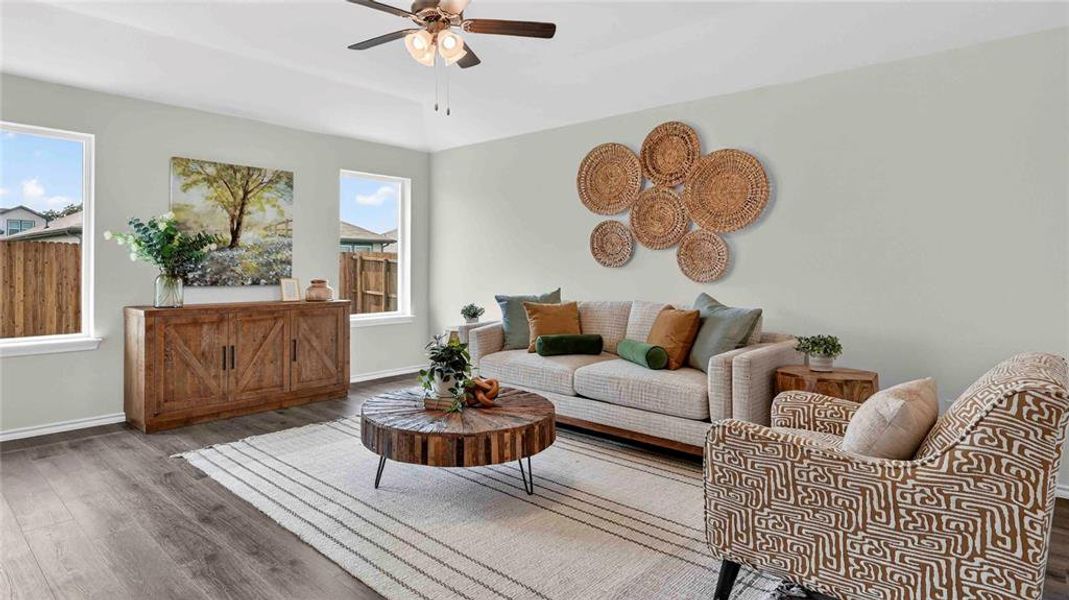 Spacious living area featuring wood-finish flooring, light neutral wall tones, and a ceiling fan with integrated lighting Spacious living area featuring wood-finish flooring, light neutral wall tones, and a ceiling fan with integrated lighting
