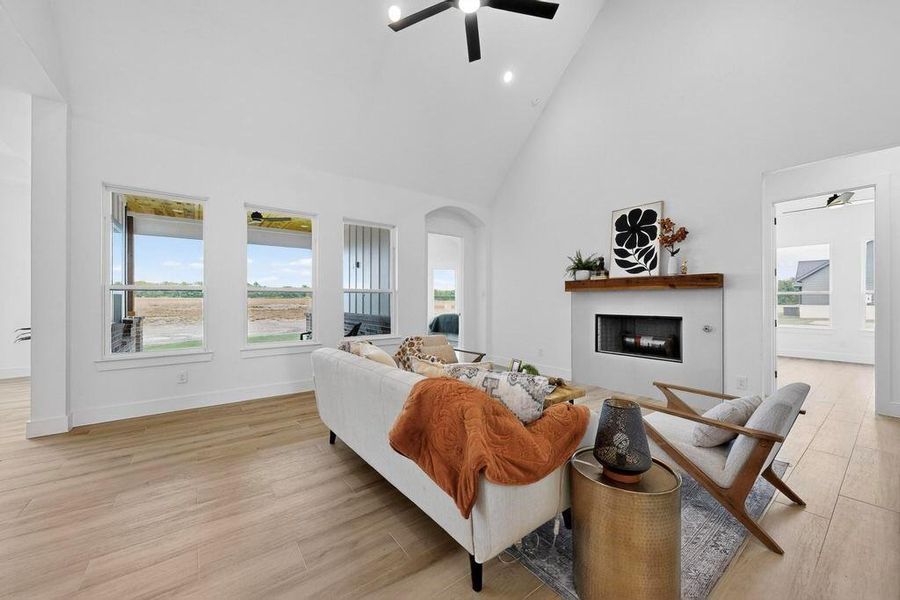 Living room featuring high vaulted ceiling, a fireplace, plenty of natural light, light wood finished floors, and arched walkways Living room featuring high vaulted ceiling, a fireplace, plenty of natural light, light wood finished floors, and arched walkways
