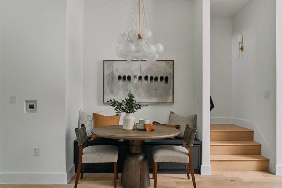 Dining area featuring a chandelier, breakfast area, stairway, baseboards, and wood finished floors Dining area featuring a chandelier, breakfast area, stairway, baseboards, and wood finished floors