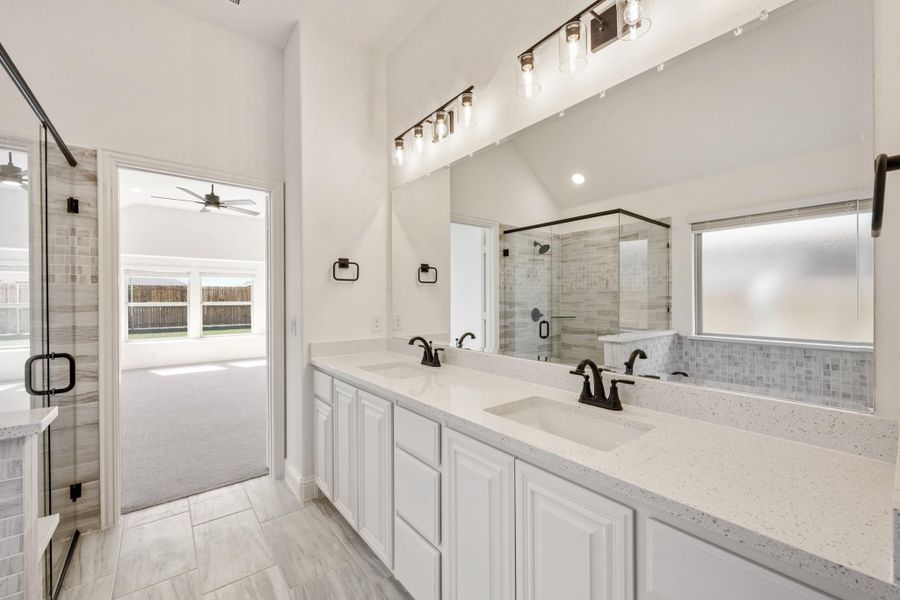Master bathroom with double vanity, white quartz countertops, glass shower, and large mirror with modern lighting Master bathroom with double vanity, white quartz countertops, glass shower, and large mirror with modern lighting