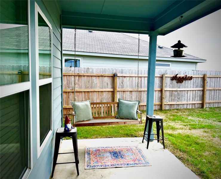 Covered patio with a concrete slab, featuring a wooden swing