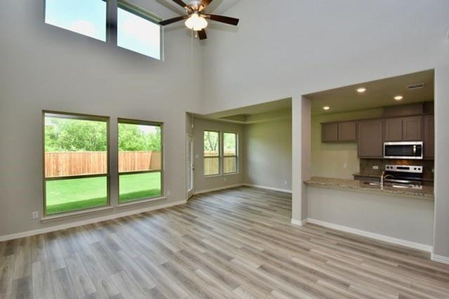 Family room with a ceiling fan, light wood finished floors, a high ceiling, recessed lighting, and lots of natural light
