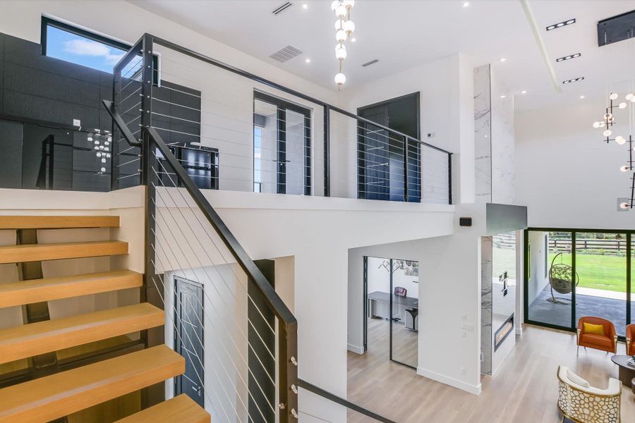 Stairs featuring wood stairs and metal railings and a towering ceiling and chandelier Stairs featuring wood stairs and metal railings and a towering ceiling and chandelier