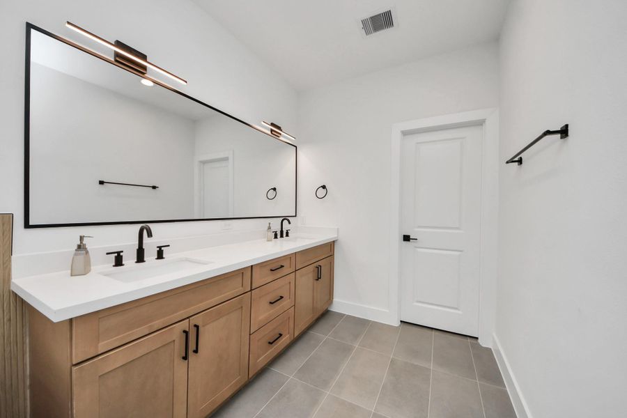 This modern bathroom offers sleek double sinks set against a spacious vanity, perfect for a stylish and functional start to your day.