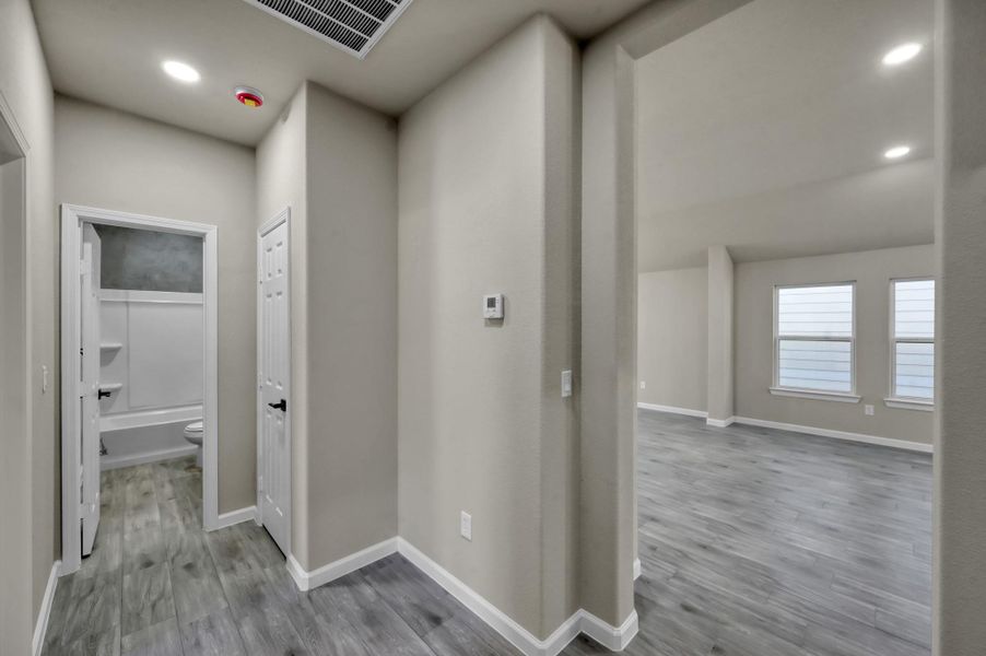 This thoughtful layout emphasizes open-concept living. The wide hallway with wood-look flooring leads past a convenient laundry or storage closet toward the light-filled main living area.