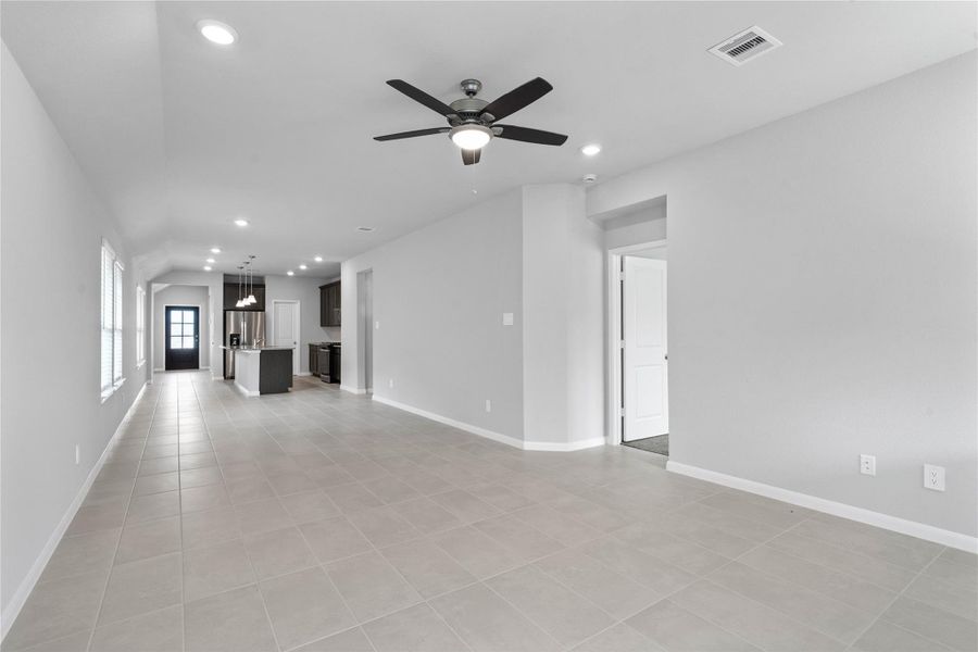 This expansive view from the back of the house showcases a seamless, open-concept layout that creates a warm and inviting path for guests, drawing the eye past the heart of the home toward the welcoming front entryway.