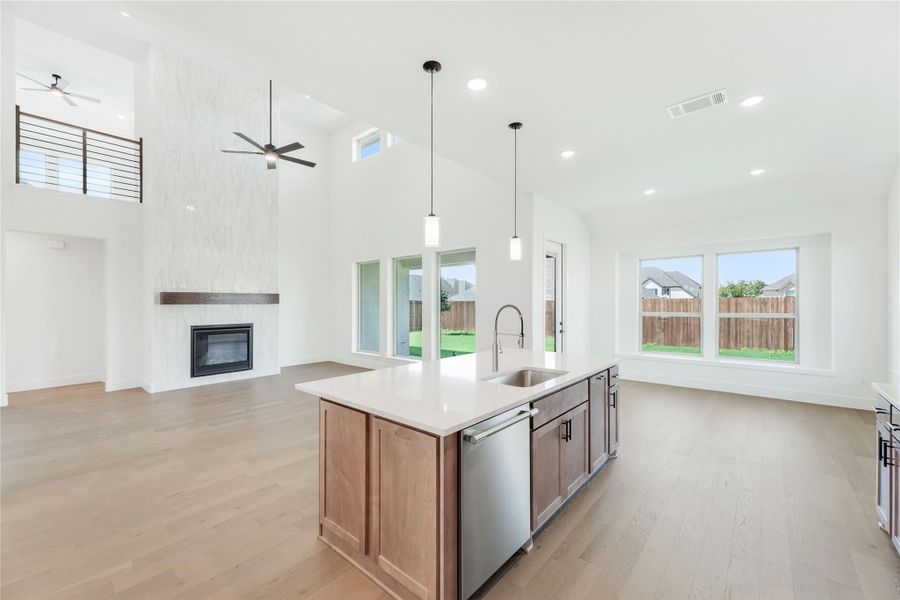 Open-concept kitchen with wood island, pendant lights, and fireplace in living area with vaulted ceiling