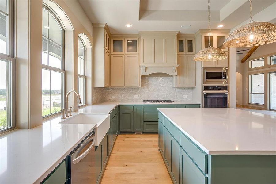 Kitchen featuring tasteful backsplash, appliances with stainless steel finishes, light countertops, green cabinets, and light wood finished floors