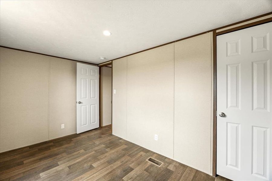 Interior room featuring wood-finish flooring, light-toned wall panels, and white paneled doors