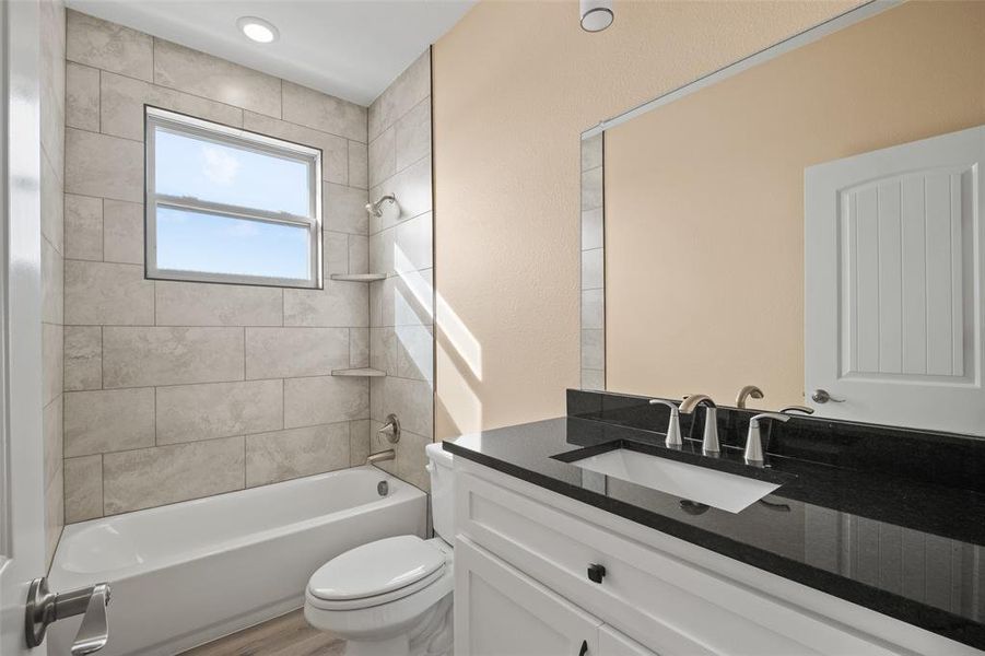 Bathroom featuring a white vanity with black countertop, undermount sink, and dual-tone fixtures Bathroom featuring a white vanity with black countertop, undermount sink, and dual-tone fixtures