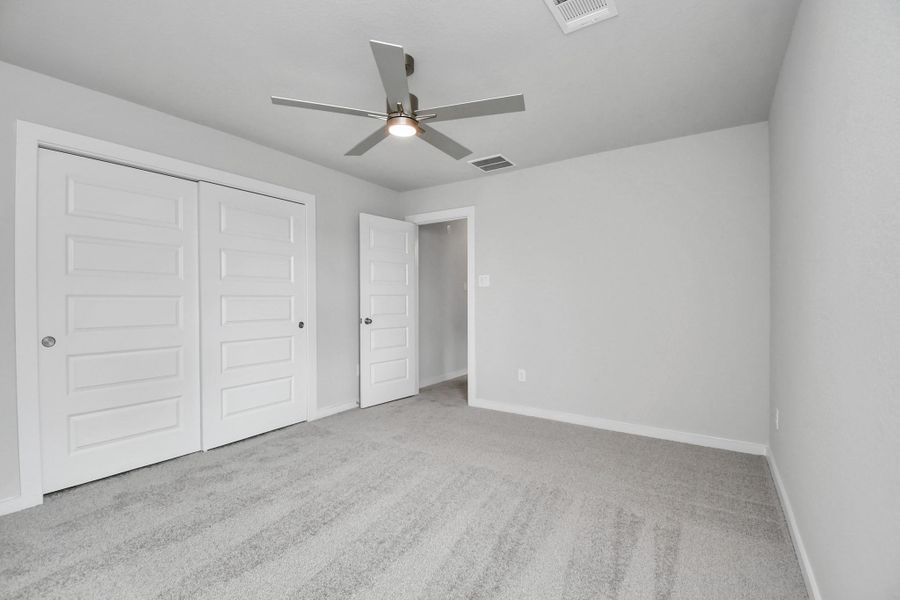 Secondary bedroom features plush carpeting, large windows that let in plenty of natural light, bright paint, and spacious closets. Sample photo of completed home with similar floor plan. Actual colors and selections may vary. Secondary bedroom features plush carpeting, large windows that let in plenty of natural light, bright paint, and spacious closets. Sample photo of completed home with similar floor plan. Actual colors and selections may vary.