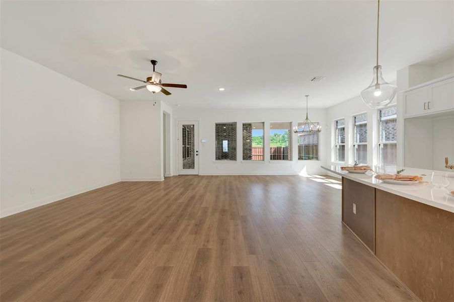 Expansive open-concept living space featuring wood-finish flooring, recessed lighting, and a ceiling fan Expansive open-concept living space featuring wood-finish flooring, recessed lighting, and a ceiling fan