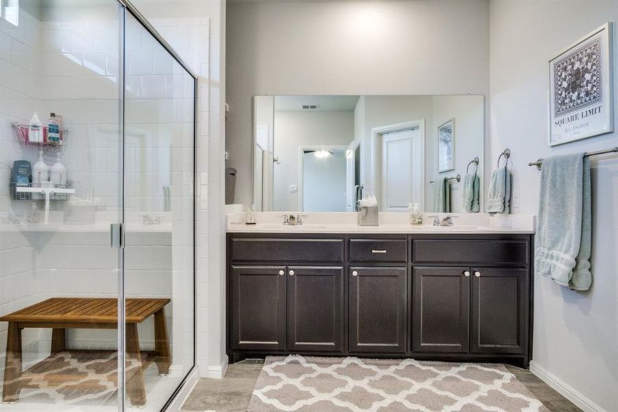 Full bathroom featuring double vanity, a shower stall, and a sink