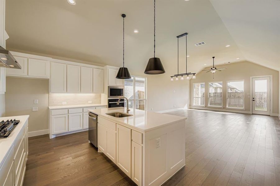 Kitchen featuring white cabinets, recessed lighting, vaulted ceiling, pendant lighting, and decorative backsplash Kitchen featuring white cabinets, recessed lighting, vaulted ceiling, pendant lighting, and decorative backsplash