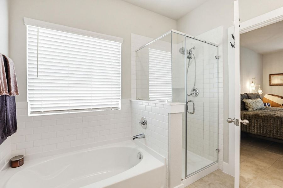 Bathroom featuring a built-in bathtub with subway tile surround, a separate glass-enclosed shower, chrome fixtures, and a window with white blinds
