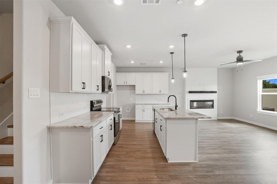 Kitchen featuring appliances with stainless steel finishes, recessed lighting, pendant lighting, light wood-style flooring, and white cabinetry