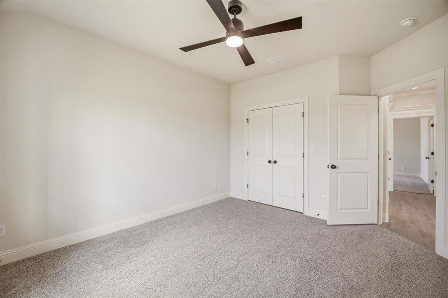 Unfurnished bedroom featuring carpet floors, ceiling fan, and a closet
