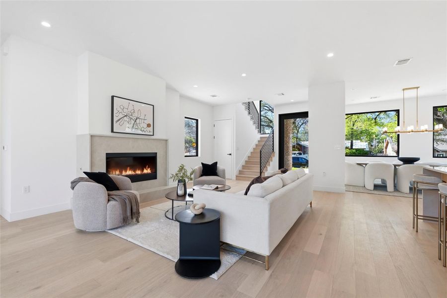 Living area featuring light wood-type flooring, a high end fireplace, and hanging lights
