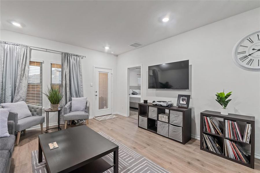 Living area with light wood finished floors and recessed lighting