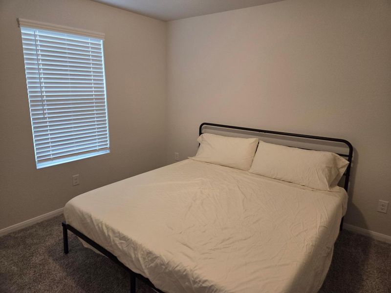 Carpeted room with a window featuring horizontal blinds