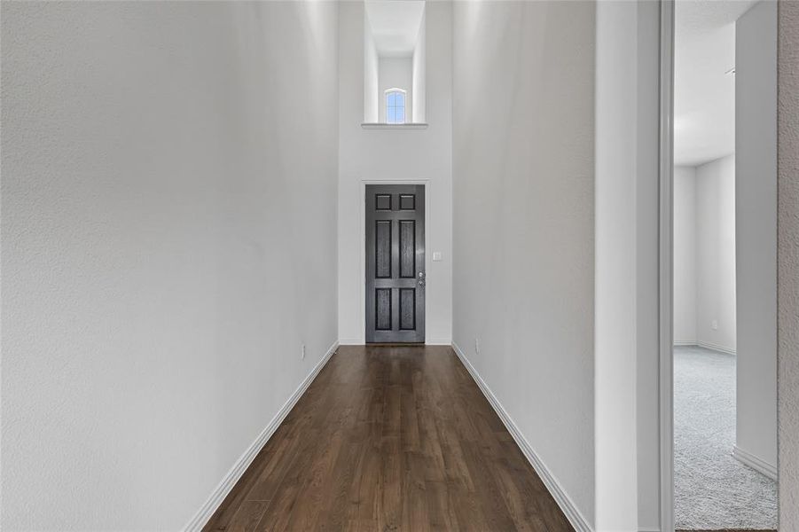 Hall featuring a high ceiling and dark wood-style flooring Hall featuring a high ceiling and dark wood-style flooring