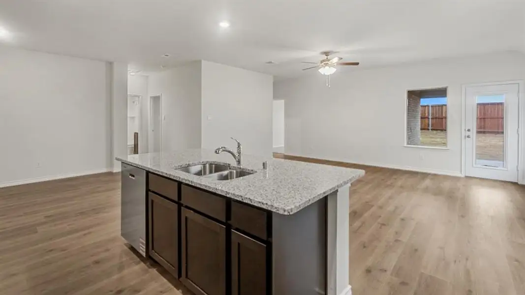 Kitchen island featuring a double-basin sink, stainless steel faucet, and integrated dishwasher