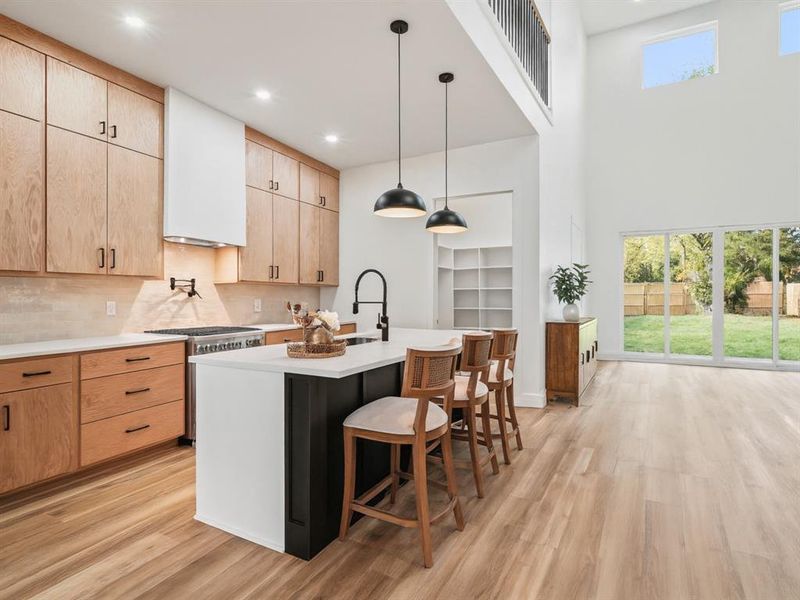 Kitchen featuring light brown cabinets, pendant lighting, a breakfast bar area, light wood-type flooring, and recessed lighting