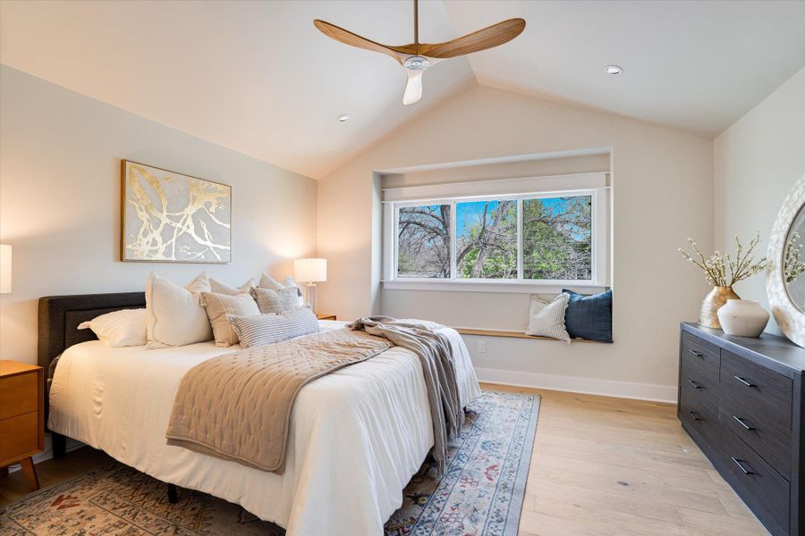 Bedroom featuring vaulted ceilings, light wood flooring, and a window seat with outdoor views Bedroom featuring vaulted ceilings, light wood flooring, and a window seat with outdoor views