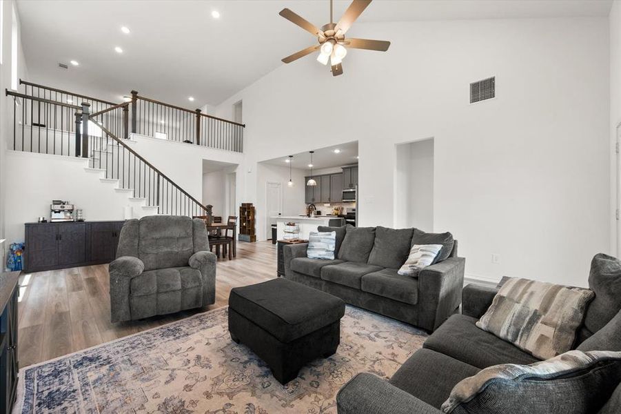 Spacious living area featuring high vaulted ceilings, light wood-finish flooring, and recessed lighting