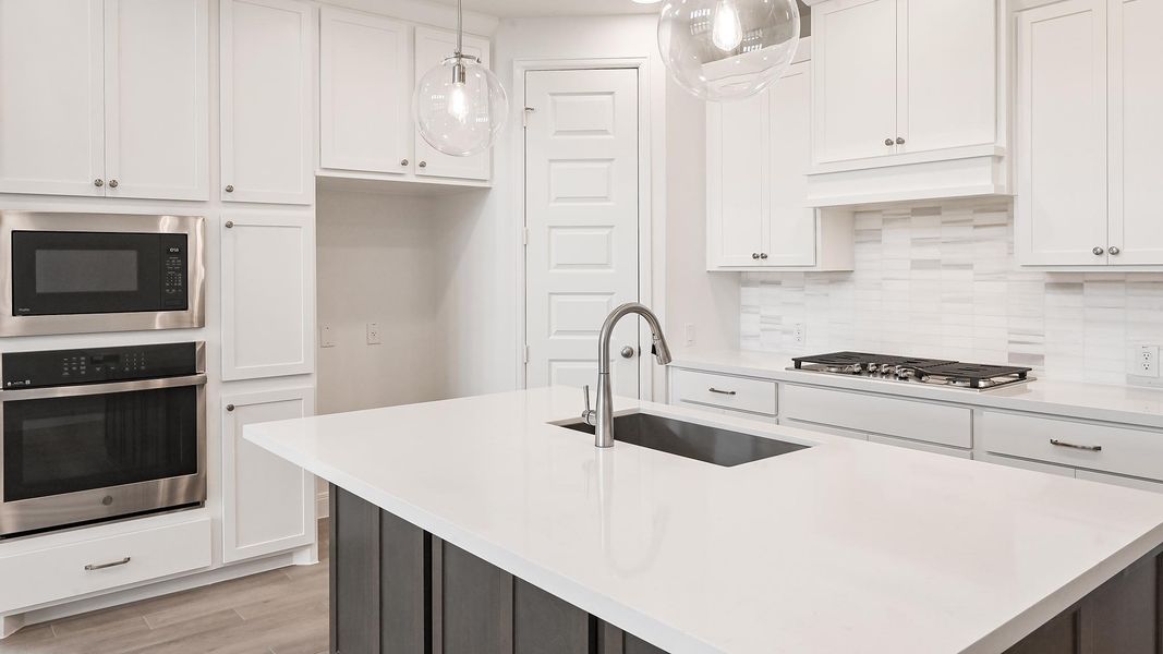 Kitchen featuring stainless steel appliances, a sink, white cabinetry, and light countertops