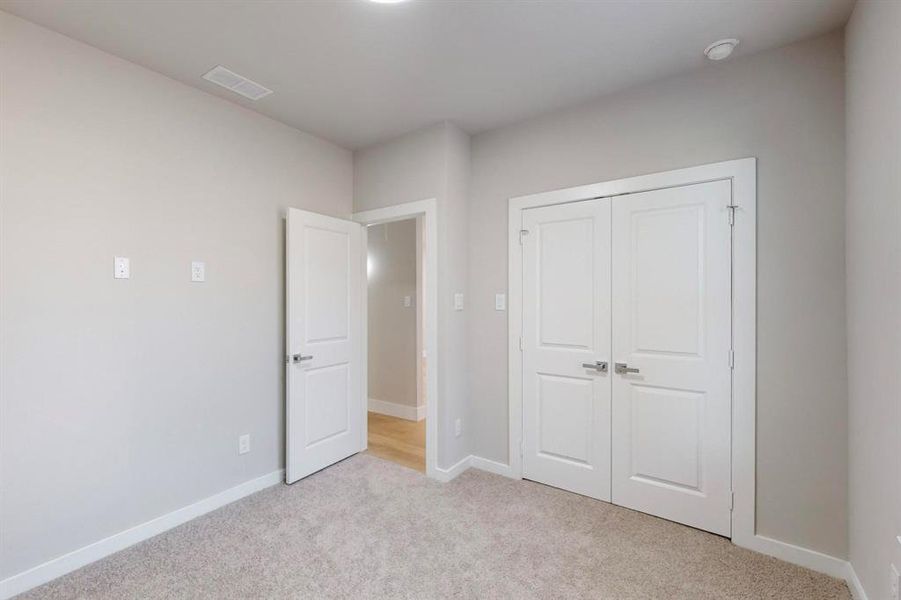 Unfurnished bedroom with light carpet and a closet