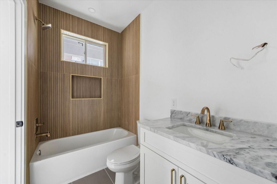 Ensuite bath for the second bedroom features dolomite countertops, wood-look tile, and a shower/tub combo.