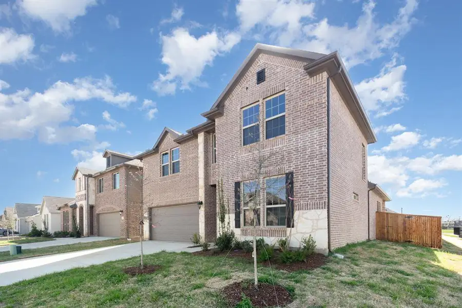 Traditional-style home featuring driveway, brick siding, a garage, and fence