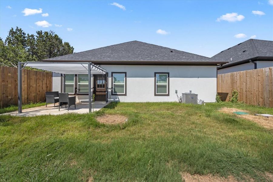 Rear view of house featuring a yard, central AC unit, and a patio area