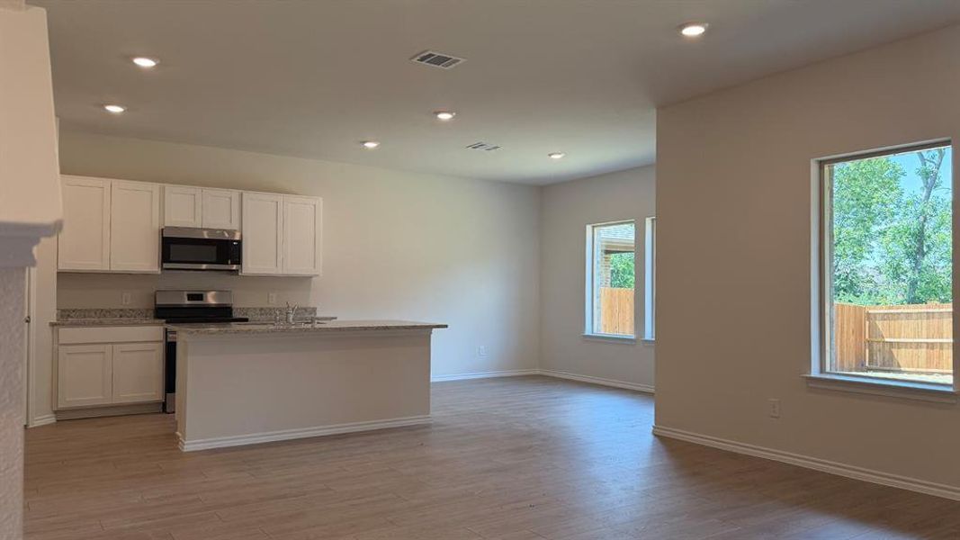 Open-concept living space with wood-finish flooring, recessed lighting, and ample natural light from multiple windows